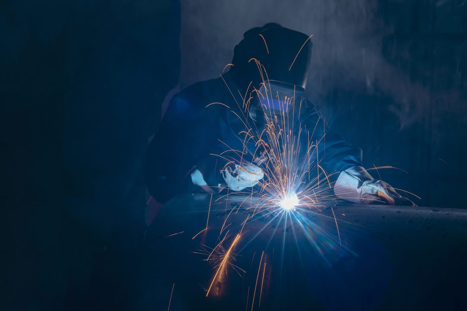 Professional welder working on a metal pipe — mobile welding field work