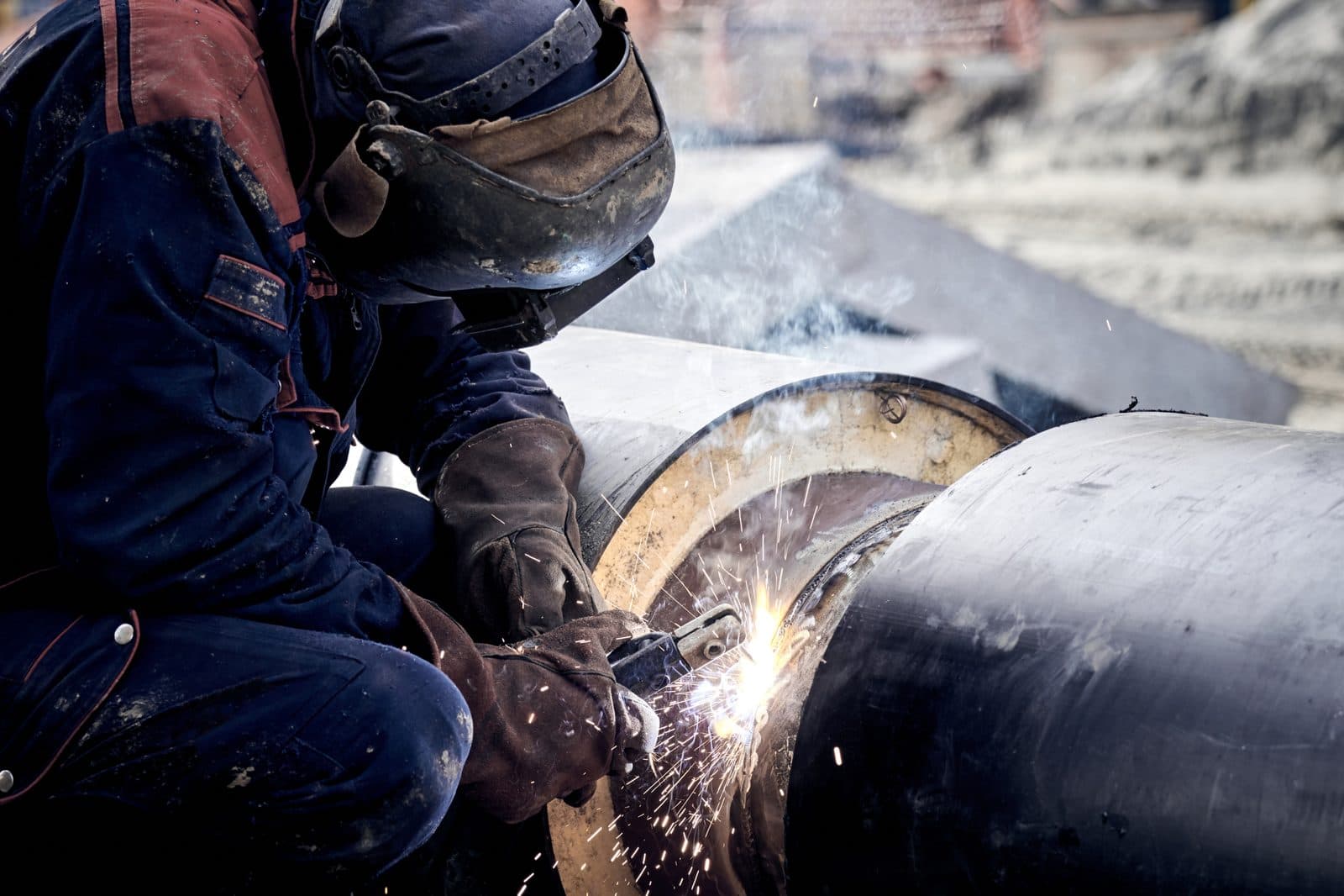 Welder arc-welding a metal pipeline under ASME Section IX